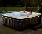 Thumnbail of Two people using Caldera Utopia spa at night