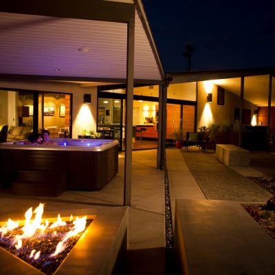 Two people in Caldera Vacanza spa with blue LED lights. Fire pit in foreground