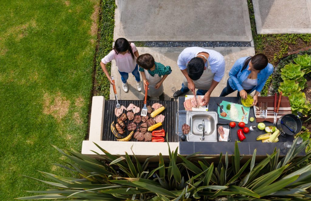 Overhead view of a family preparing food together in a modern outdoor kitchen.